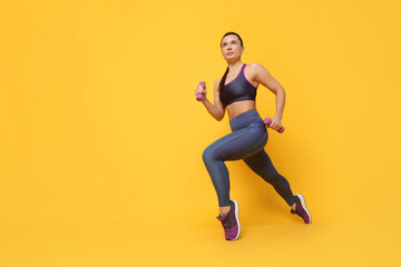 Fototapeta na wymiar Beautiful woman in sportswear training with dumbbells on yellow background, low angle view. Space for text