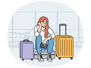 Upset woman airport passenger sits among tourist suitcases and waits for plane that is late due to bad weather. Concept of flight cancellation causing inconvenience to airport passengers