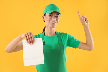 Fast-food worker with paper bag on orange background