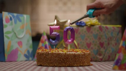 Candle shaped as number 50 lights up on a birthday cake surrounded by gifts. A festive and vibrant scene celebrating a golden milestone in style
