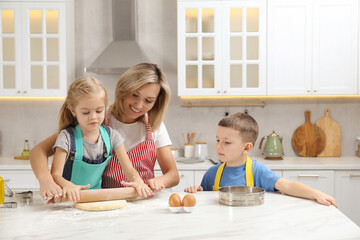 Children helping their mom making cookies in kitchen at home