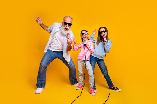 Happy family group singing karaoke on joyful yellow background