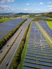 Aerial view of solar panels located along a highway, with a landscape of green fields and hills....