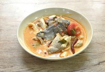 boiled bass fish head and mushroom in tom yum soup on plate