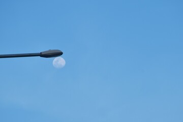 moon under electric lamp pole on cloud and sky background