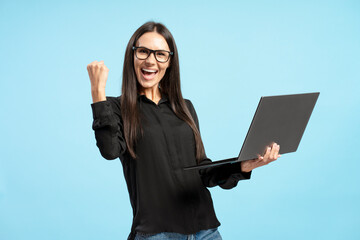 Excited businesswoman celebrating success with laptop and fist pump