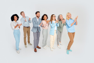 Obraz premium Diverse group of business professionals applauding together in a cheerful atmosphere on a white background