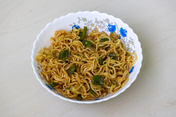 Delicious fried noodles with green bell pepper, tomato, and chili, served in a white bowl.