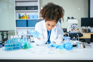 An African American female scientist in a white coat and blue gloves smiles confidently, holding a test tube with blue liquid. She conducts drug testing and medical research in a laboratory