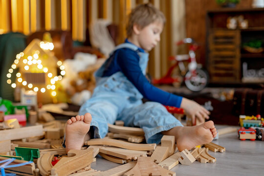 Child, cute boy, playing with toys in a playroom, focus on his feet