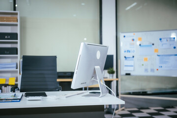 An empty desk with a computer displaying a graph on the screen, a tablet placed on the table, and a chair positioned near. The workspace is neat and ready for use