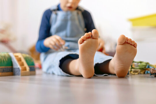 Child, cute boy, playing with toys in a playroom, focus on his feet