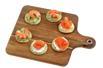 Des amuse-bouches faits maison présentés sur une planche à découper en bois isolée sur fond...