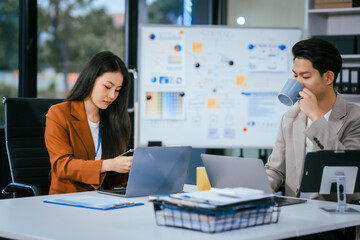 Young businessman and woman are working together at a table, discussing a proposal for cooperation. They review documents focused on business marketing strategies, finance, effective collaboration