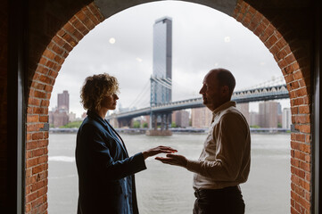 People by the window with Manhattan Bridge in the background, Brooklyn District in New York City -...