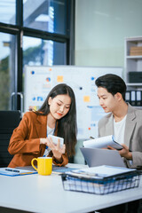 Young businessman and woman are working together at a table, discussing a proposal for cooperation. They review documents focused on business marketing strategies, finance, effective collaboration