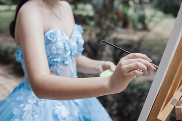 beautiful teenage girl in dress and crown painting a picture on canvas