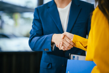 A businessman and businesswoman shake hands during a meeting at the office,signifying collaboration.They discuss strategies, agreements,opportunities to drive business growth strengthen professional
