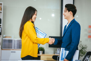 Fototapeta premium A businessman and businesswoman shake hands during a meeting at the office,signifying collaboration.They discuss strategies, agreements,opportunities to drive business growth strengthen professional