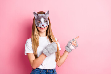 Young woman wearing cat mask and gloves styled for cosplay against pink background