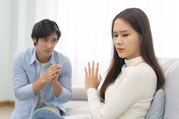 Family problems, Asian women cover her face and sit separately from husband feel disappointed after quarrels at home.