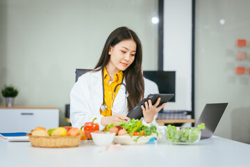 Two nutritionists,female and male, work in a hospital, analyzing vegetable and fruit salads, offering online advice, helping patients embrace clean eating habits and weight control for better health