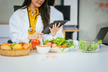Two nutritionists,female and male, work in a hospital, analyzing vegetable and fruit salads,...