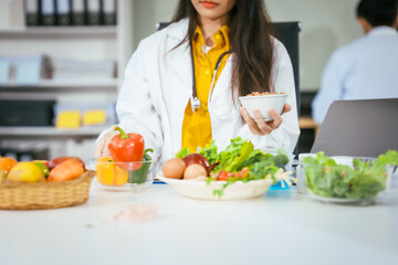 Two nutritionists,female and male, work in a hospital, analyzing vegetable and fruit salads,...