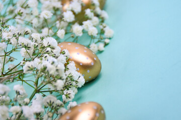 Decorative composition with golden Easter eggs with white polka dots located among gypsophila...