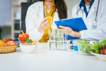 Two nutritionists,female and male, work in a hospital, analyzing vegetable and fruit salads,...