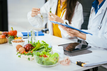 Two nutritionists,female and male, work in a hospital, analyzing vegetable and fruit salads, offering online advice, helping patients embrace clean eating habits and weight control for better health