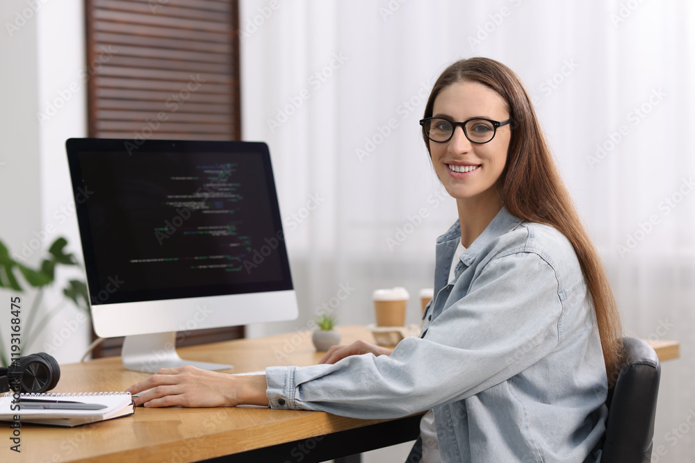 Poster programmer working on computer at wooden desk indoors
