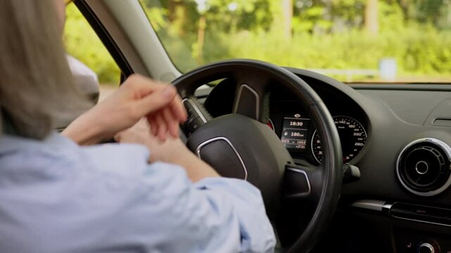 Close up back view unrecognizable Caucasian elderly woman senior gray haired lady car driver female hands holding steering wheel dashboard driving automobile steer machine ride turning inside vehicle