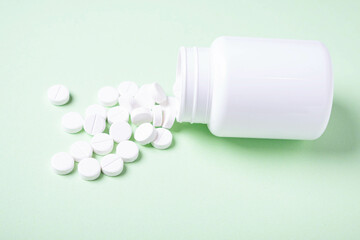 Tablets from the bottle are scattered on a light background