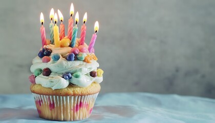 A charming cupcake tower with colorful candles and frosting isolated on a soft blue backdrop