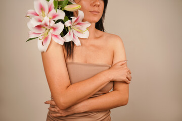 A dark-haired European woman holds a bouquet of lilies on her shoulder, her eyes closed as if...