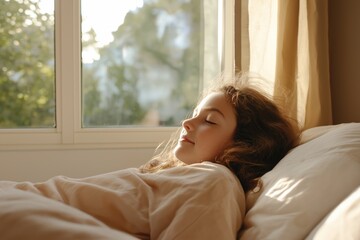 A woman is sleeping on a bed with a window behind her. The window is open, letting in sunlight and creating a peaceful atmosphere