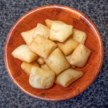 Top view of the national pastries of the peoples of Central Asia - boorsok (baursak), these are plump square dough products fried in vegetable oil, they lie in a wooden round plate.