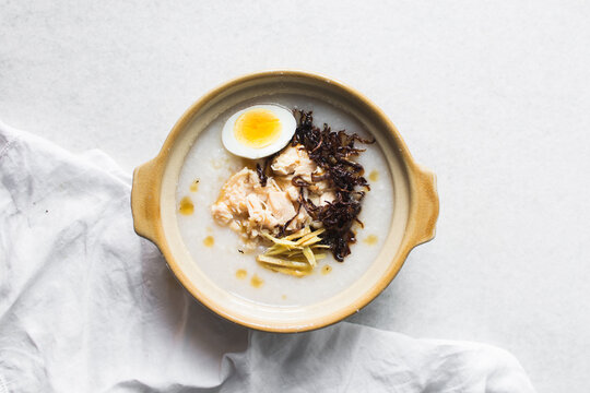 Overhead view of rice chicken congee in a clay pot, top view of rice and chicken porridge, chinese chicken congee, korean dak juk or japanese okayu in a claypot