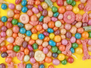 Fototapeta premium A vibrant assortment of multicolored candy set against a cheerful yellow background, vibrant, snack, fun