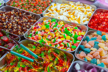 Colorful array of assorted gummy candies presented in containers, offering a variety of shapes and flavors for a sweet treat experience