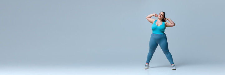 Banner. Woman in blue top and leggings standing confidently, stretching arms outward with smile,...