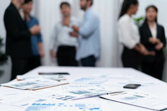 Business intelligence and analyzed financial data visualized on papers with blur background of analyst team utilizing BI Fintech in meeting room for business insight and marketing planning. Prudent