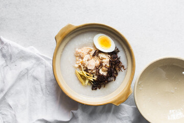 Overhead view of rice chicken congee in a clay pot, top view of rice and chicken porridge, chinese chicken congee, korean dak juk or japanese okayu in a claypot