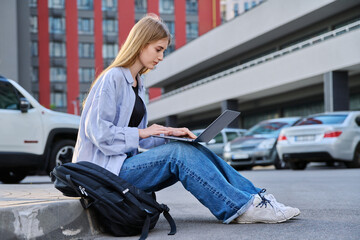 Young female college student using laptop computer outdoor