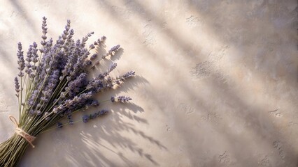 A sunlit bunch of lavender flowers rests on a textured beige surface