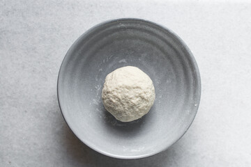 Overhead view of noodles dough in a grey bowl, top view of homemade biang biang noodles, process of making hand pulled noodles