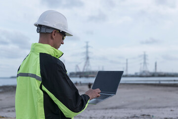 Engineers wear uniform standing near the open trunk of a vehicle hand holding computer laptop, survey inspection work plant site use tablet see detail of work with oil refinery background.