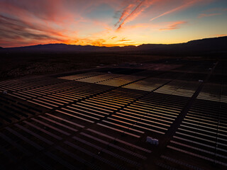 Dramatic sunset over massive solar farm, aerial view.