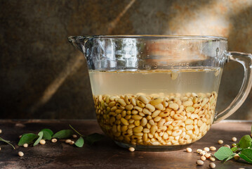 soaked soybean in a glass bowl on brown rustic table.